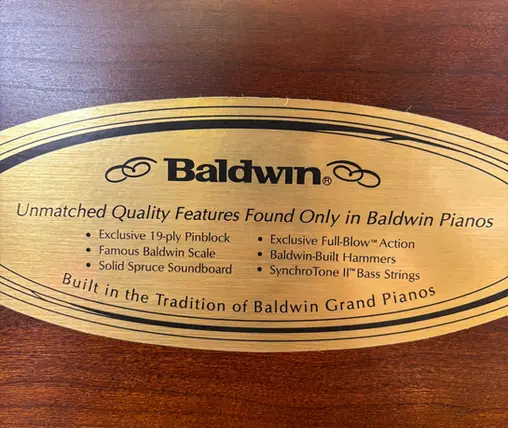 Close-up of Baldwin Studio Upright Piano quality features sticker at Rockafellow Piano in San Antonio, Texas.