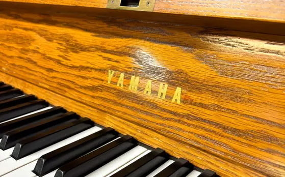 Yamaha P22 Studio Upright Piano fallboard with Yamaha decal close-up in brown wood at Rockafellow Piano in San Antonio, Texas