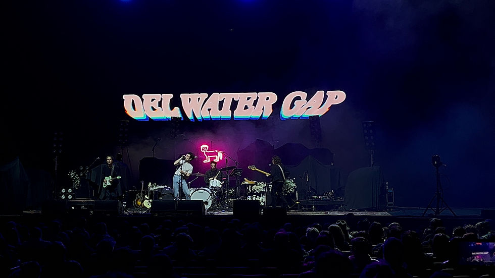 A man stands on the left side of a stage with the words "Del Water Gap" projected behind him.