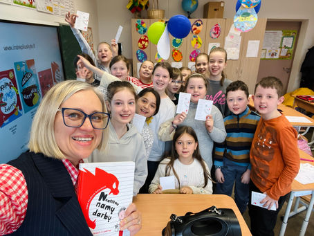 Indrė Pliuškytė-Zalieckienė pozuoja su trečiokų klase laikydama knygą