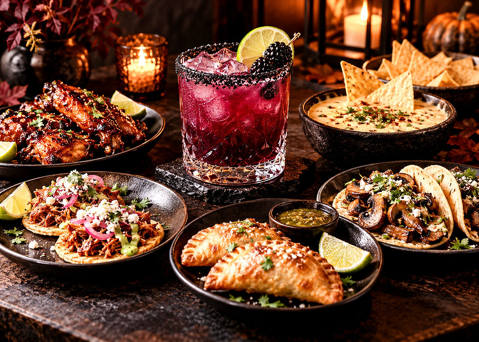 Festive spread of smoky, salty, or gently spicy tacos, wings, queso, empanadas, and chips around a midnight blackberry margarita by candlelight