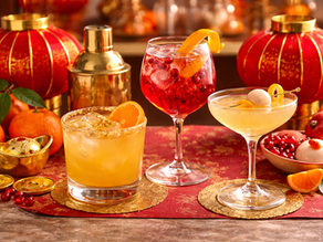 Lunar New Year cocktail setup with red lanterns, gold accents, and citrus garnishes on a festive bar table