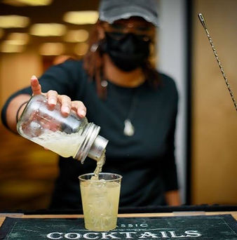 A bartender mixologist serving and straining a cocktail
