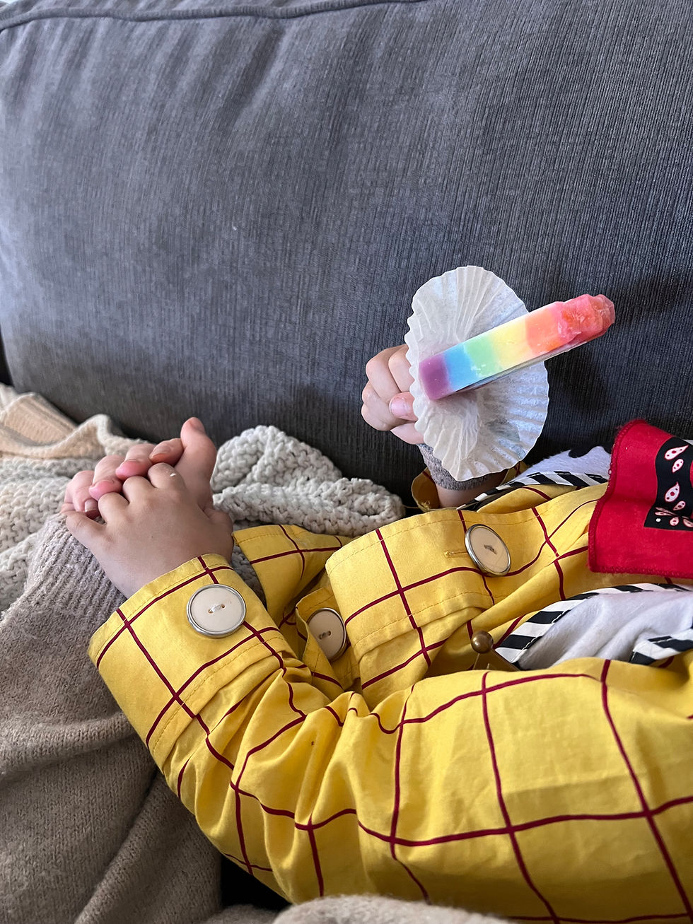 Close-up of a mother gently holding her toddler’s hand while the child holds a popsicle during tonsillectomy recovery.