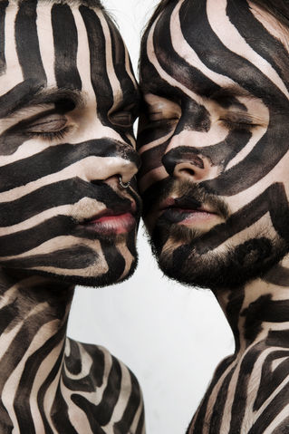 Photograph of two people with their faces painted by The Line Girl with black abstract lines