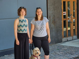 Två kvinnor och en hund står en sommardag på kullersten utanför Stenkrossens Kulturhus i Lund