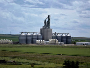SWT inland grain terminal with steel grain silos, elevator structures, and industrial buildings under a cloudy sky.