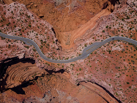 A winding road through a red, rocky desert as seen from above