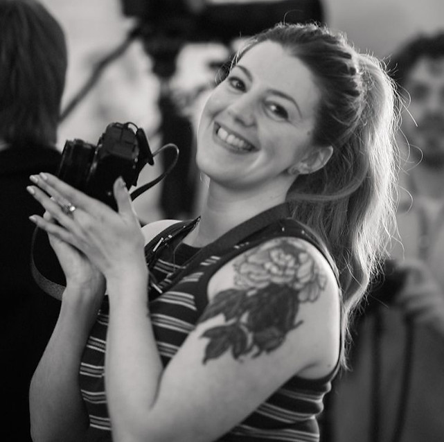 Ally Thornton smiling and holding a camera, while working as a Camera Operator