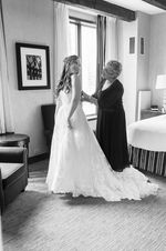 Woman helping a bride into her wedding dress