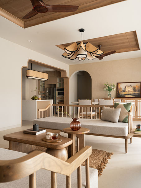 minimalist Pune apartment with natural light and hill views, Cedar Cane residence by The Arch Studio with timber and cane interiors, modern living room with curved bookshelf and fluted furniture design, open plan living dining kitchen with ashwood finishes and coffered ceiling, terrazzo quartz kitchen island in contemporary Indian home, balcony with swing and Buddha sculpture overlooking city hills, master bedroom with dark wood veneer and nature inspired decor, cane lighting corridor with handcrafted design elements, children’s bedroom with pastel tones and smart storage solutions, second bedroom with Kalakarihaath wallpaper and cane bed design, modern apartment blending Dehradun nostalgia with minimalist interiors, light filled home with natural materials and calm aesthetic