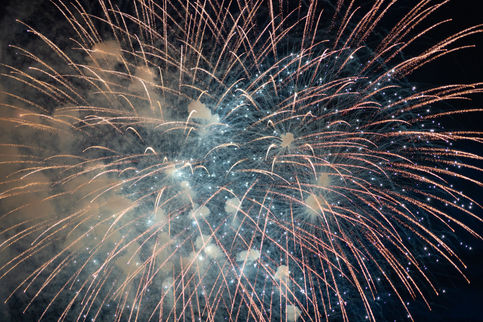 Bright gold and white fireworks streaking across the dark sky