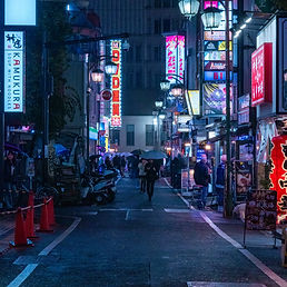 Bustling nighttime street in Tokyo, Japan, illuminated by neon signs and filled with people.