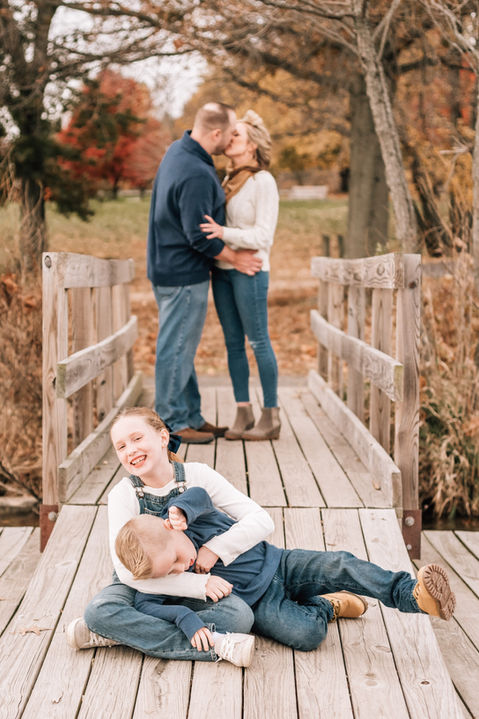 mom and dad kiss while their kids laugh in front of them