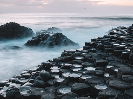 A breathtaking view of the Giant's Causeway at dawn, with its iconic rock formations bathed in warm, golden sunlight.