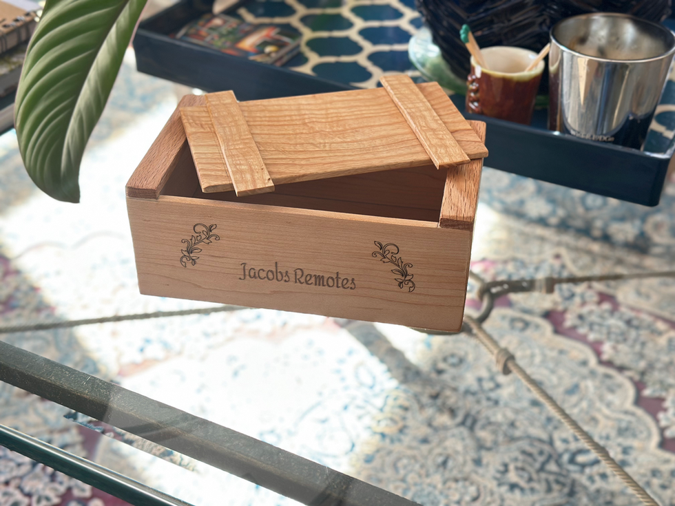 Wooden media remote storage box labeled "Jacobs Remotes", Artisan-Made Wooden Home Decor, placed on glass table.