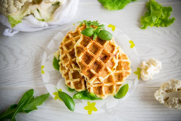 mit-blumenkohl-zubereitete-gemuesewaffeln-auf-einem-teller-auf-einem-holztisch_230573-2933