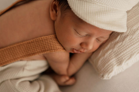 Gros plan sur le visage d’un nouveau-né dormant avec bonnet tricoté, lumière douce, séance naissance à Le Meux près de Compiègne, Chantilly et Crépy-en-Valois.
