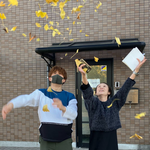 二人の人がイチョウの落葉を舞い散らせている様子