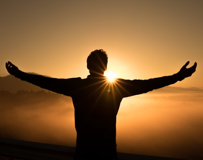 Personne heureuse, ouvrant les bras devant un coucher de soleil