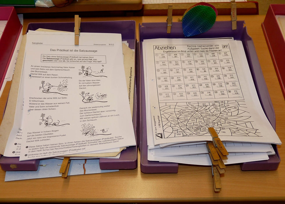 Unterrichtsmaterialien mit Arbeitsblaettern in lila Ablagekoerben im Klassenzimmer