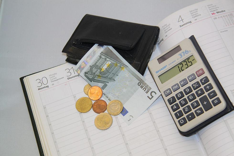 Geldbeutel mit Euromuenzen und Scheinen auf einem Kalender neben Taschenrechner