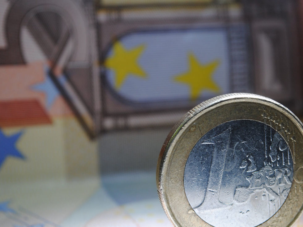 Eine Euro-Münze steht auf einem 50-Euro-Schein vor der EU-Flagge