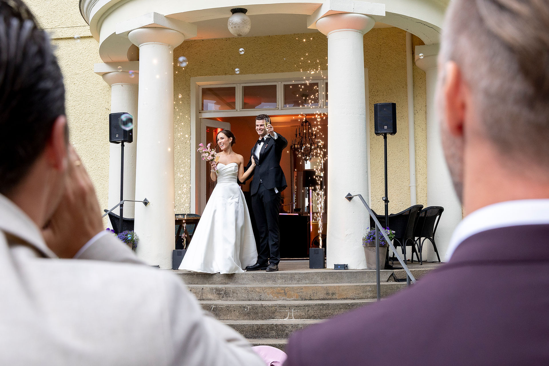 Gut Schloss Golm Foto des Hochzeitspaares auf der Bühne beim Anstoßen mit den Gästen.