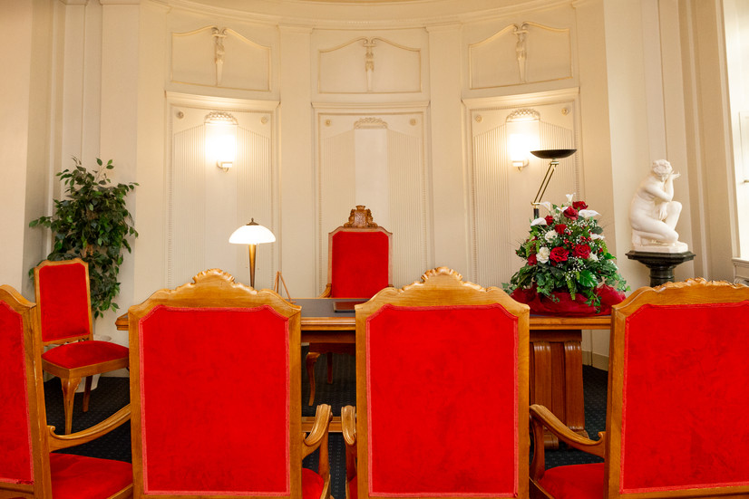 Foto des roten Trauzimmers im Büro Schöneberg in Berlin, davor der Schreibtisch von Stendesbeamtin. Das Trauzimmer ist gut fotografiert und leer.