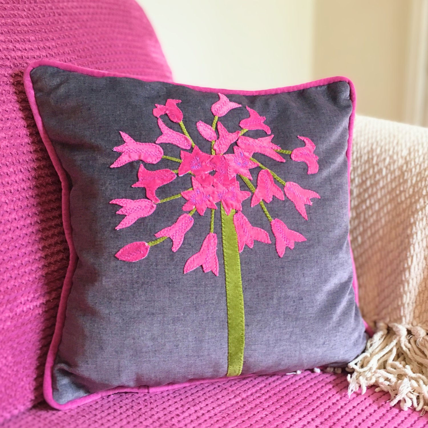 Handmade velvet cushion agapanthus design in grey and pink on sofa