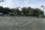 Tennis court with net ready for play with trees and blue sky background