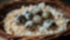 Quail eggs in a woven basket with wood shavings