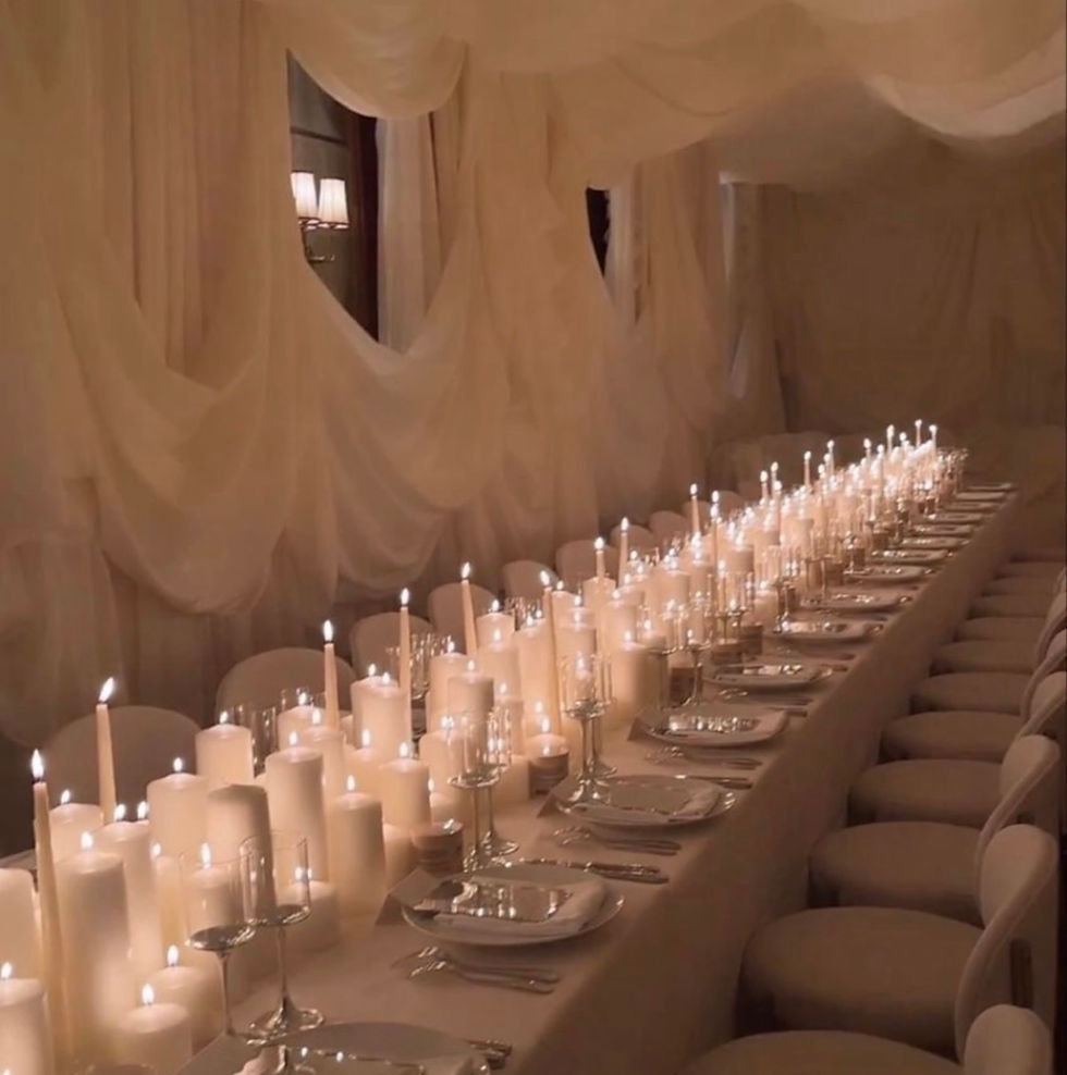 Candlelit banquet table beneath draped ivory fabric