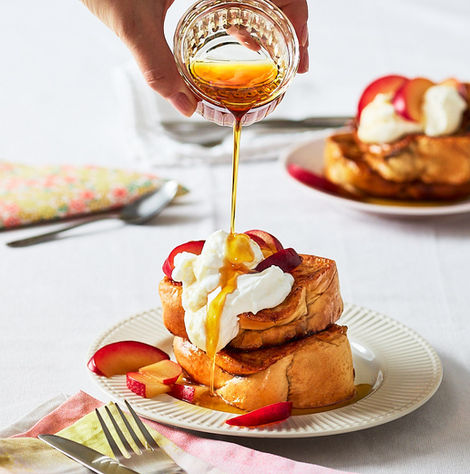 Brioche French Toast wird mit Ahornsirup übergossen, getoppt mit Sahne.