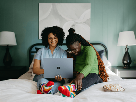 Couple sat in bed laughing while planning their wedding