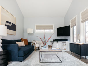 Light-filled living room with a deep blue sofa, neutral rug, modern coffee table, and carefully layered decor creating a balanced and refreshed space