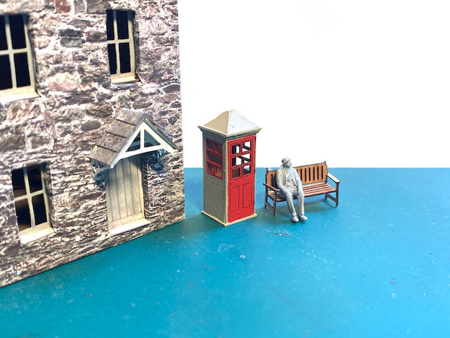 Model cottages with old phone box and man sitting on bench
