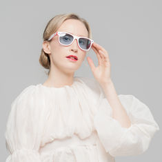 Studioaufnahme einer Frau mit weisser Sonnenbrille und transparentem Oberteil