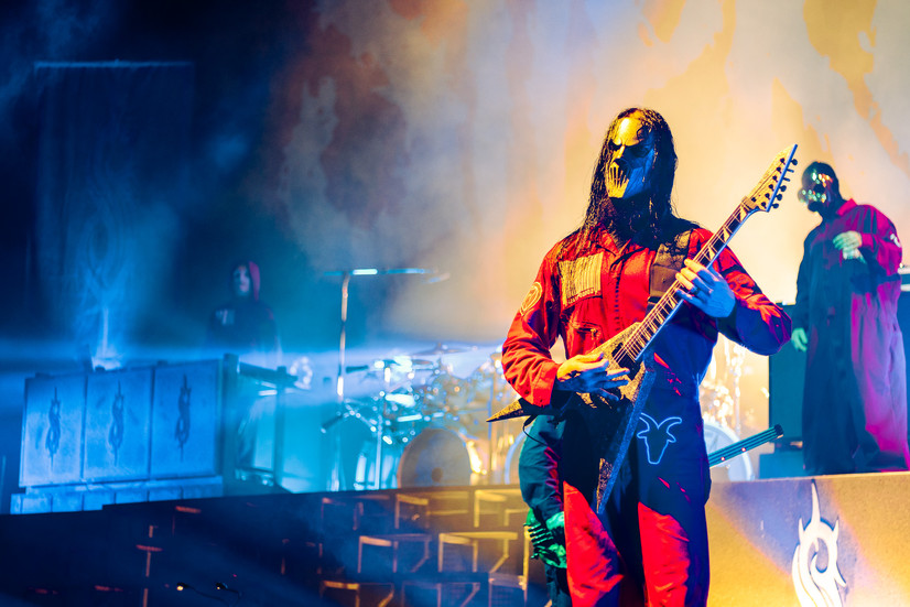 Slipknot's Seven playing the guitar on stage with red jumpsuit