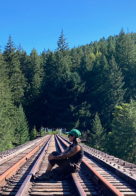 Tanya Master sitting on railway tracks surrounded by forest