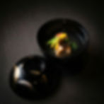 Elegant black bowl with delicate meal in broth, lid