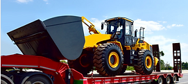 Yellow front loader secured on a red flatbed trailer for transport
