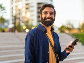 smiling man holding phone in urbanenvironment