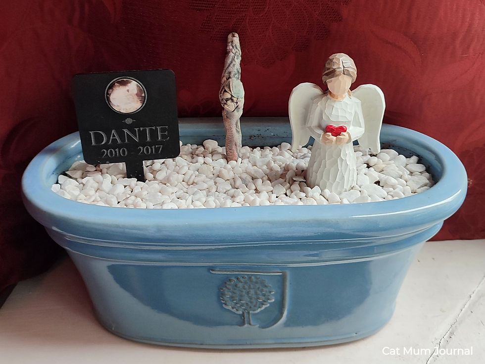 Blue planter with white pebbles, an angel figurine and a plaque.