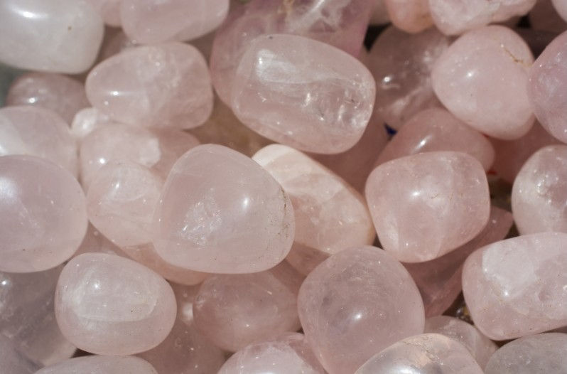 Smooth, polished rose quartz stones piled closely together.