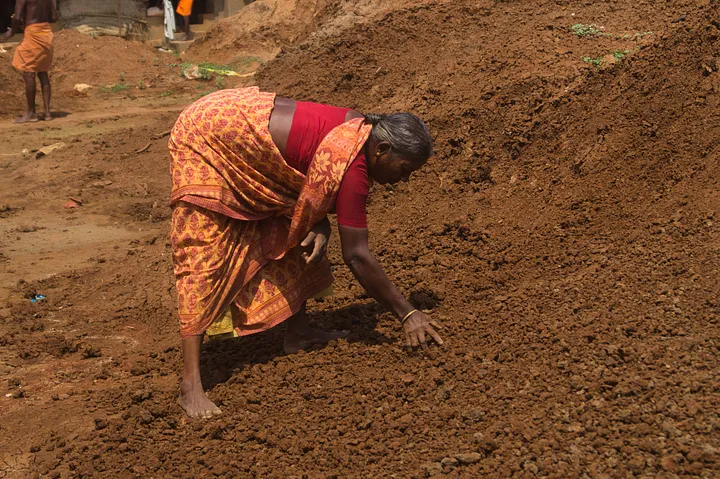 a woman handpicking stones from mud