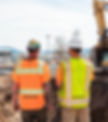Two construction workers in high-visibility safety clothing review an in-progress excavati