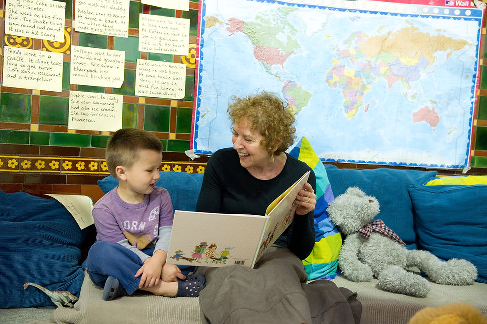 Smiling woman reads children's book to young boy with world map.