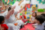 Female teacher engaging diverse young children during story time in classroom.
