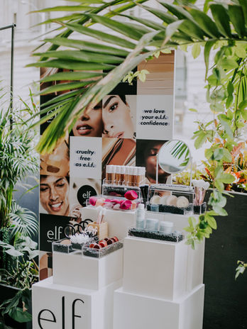 e.l.f. cosmetics retail display with tropical greenery and product pedestals.